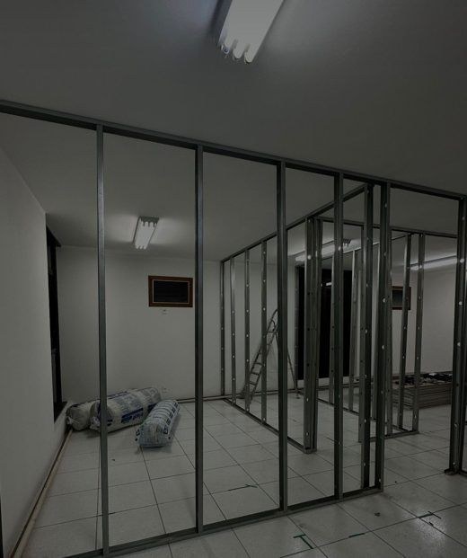 Obra da clínica: estrutura de divisórias em perfis de metal numa sala com piso de cerâmica.